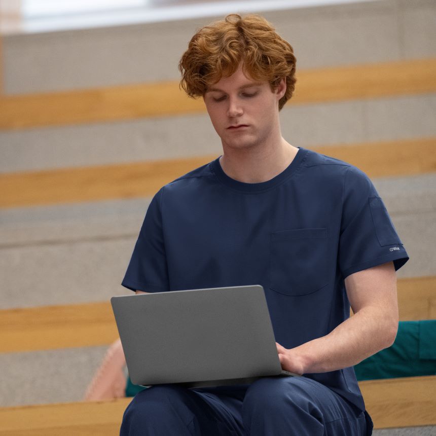 man in navy blue scrubs on laptop 