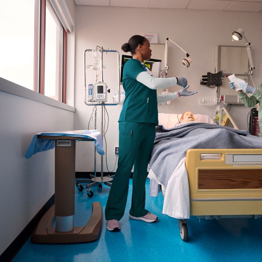 Nurse in caribbean scrubs attending to a patient in a hospital room.